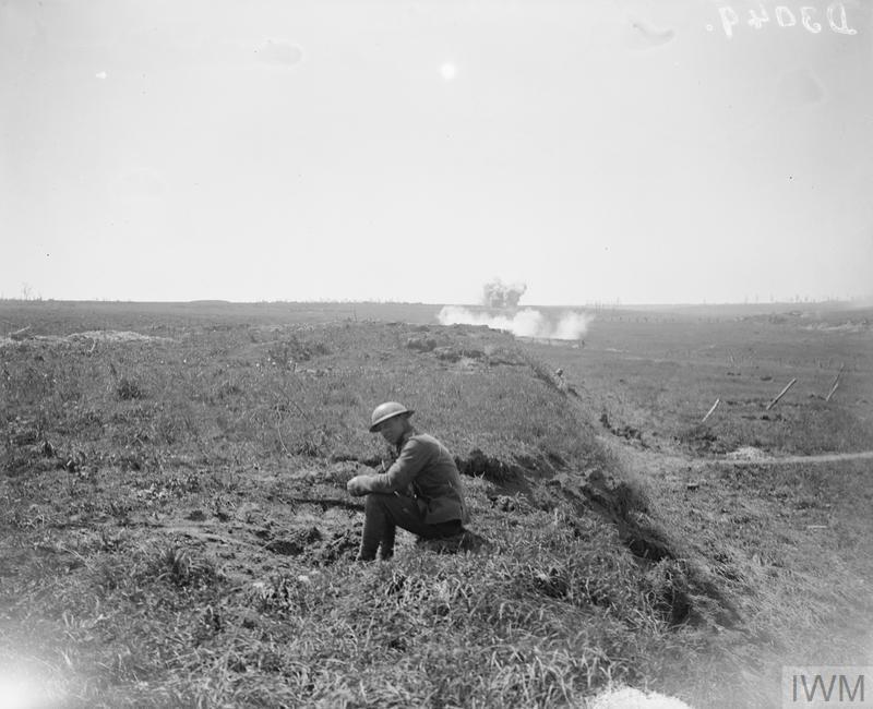 A British First World War soldier sits on a Somme battlefield while a German shell explodes in the background.