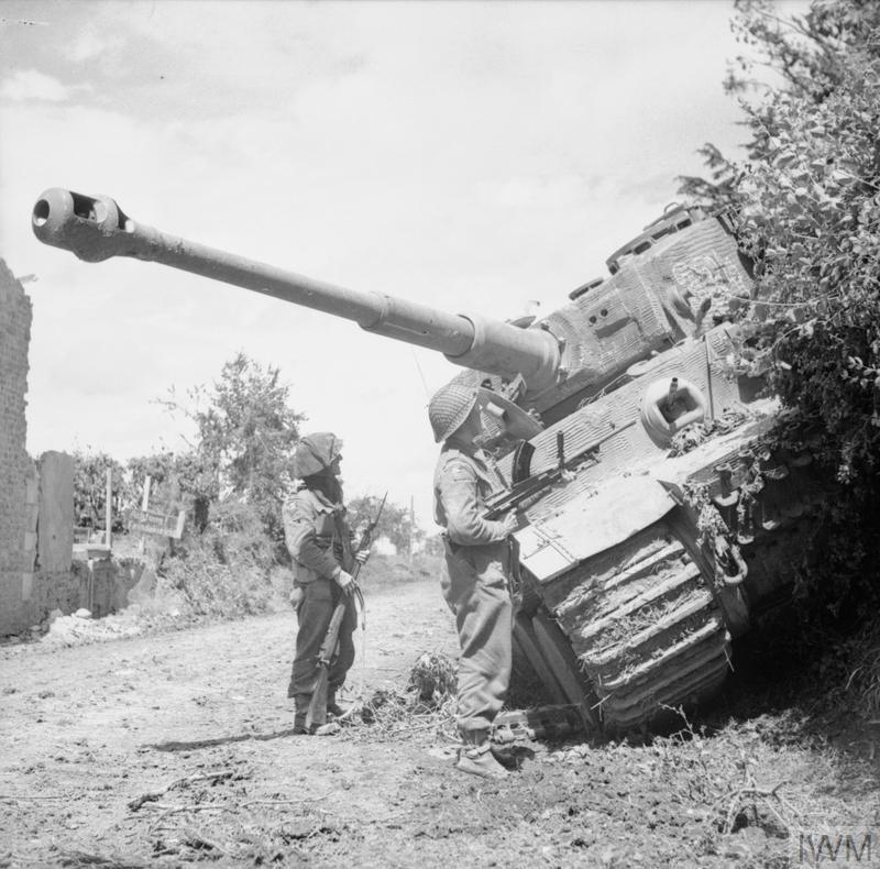 Two British soldiers inspect a knocked out Tiger Tank during Operation Epsom.