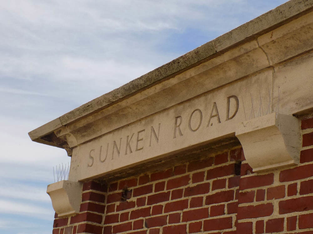Close up of the "Sunken Road" inscription carved into the pediment of the red brick entry building of Sunken Road Cemetery, Contalmaison.