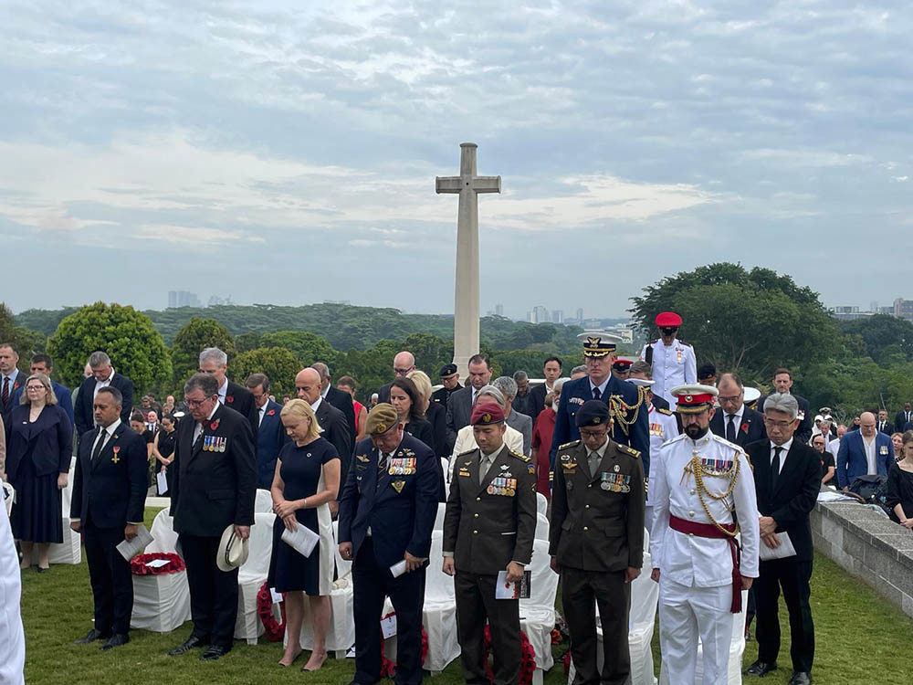 Military figures, diplomats and civilians dip their heads in mourining in front of the Cross of Sacrifice in Kranji War Cemetery, Singapore.