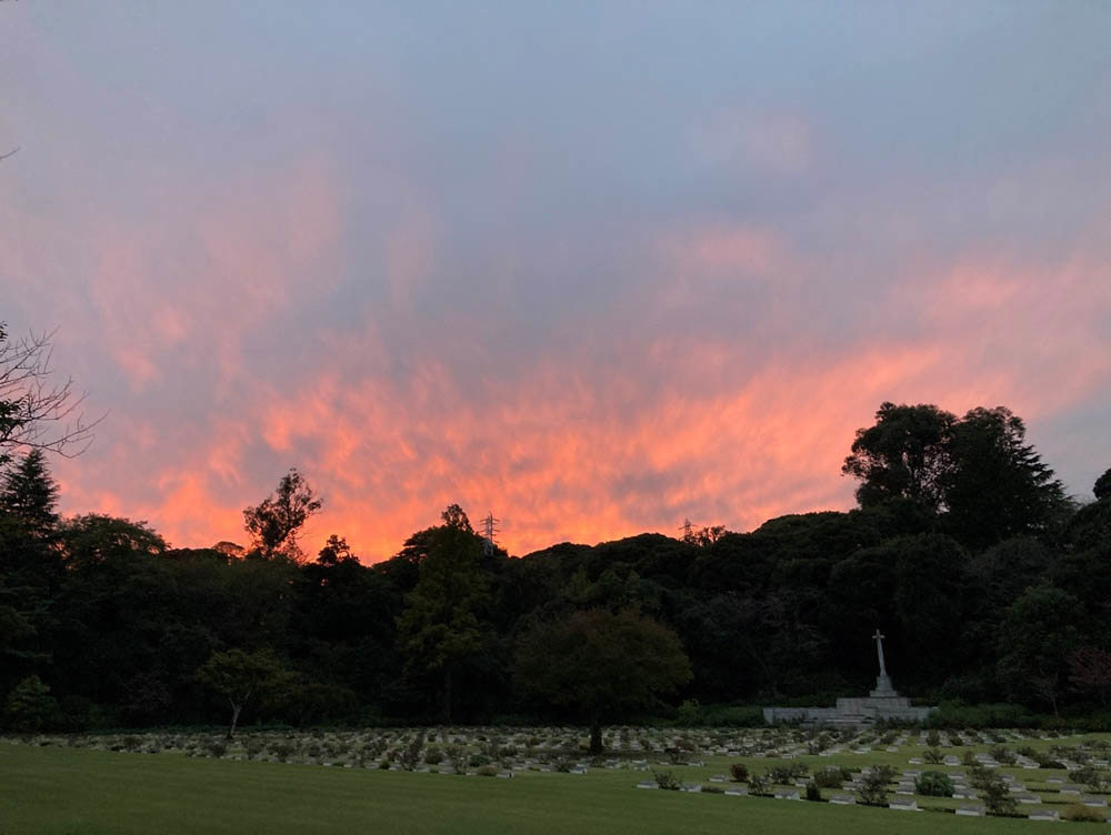A sunset gives a blood-orange glow of clouds in the dark sky above Yokohama War Cemetery.