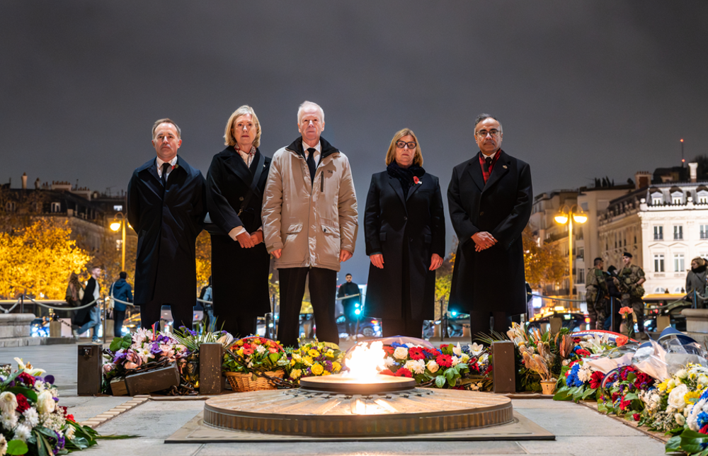 Digniataries look at the eternal flame under the Arc de Triomphe.