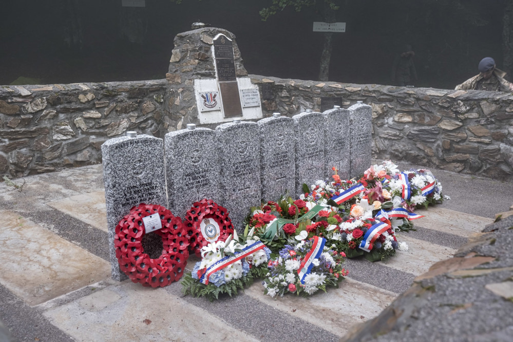 Row of CWGC headstones garlanded with wreaths and floral tributes.