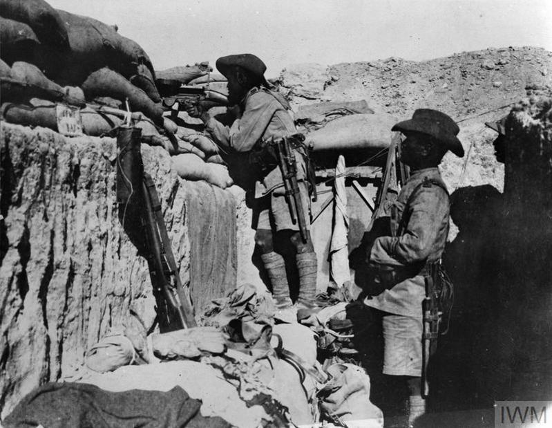 Gurkha soldiers manning a Lewis machine gun emplacement in a WW1 era trench.