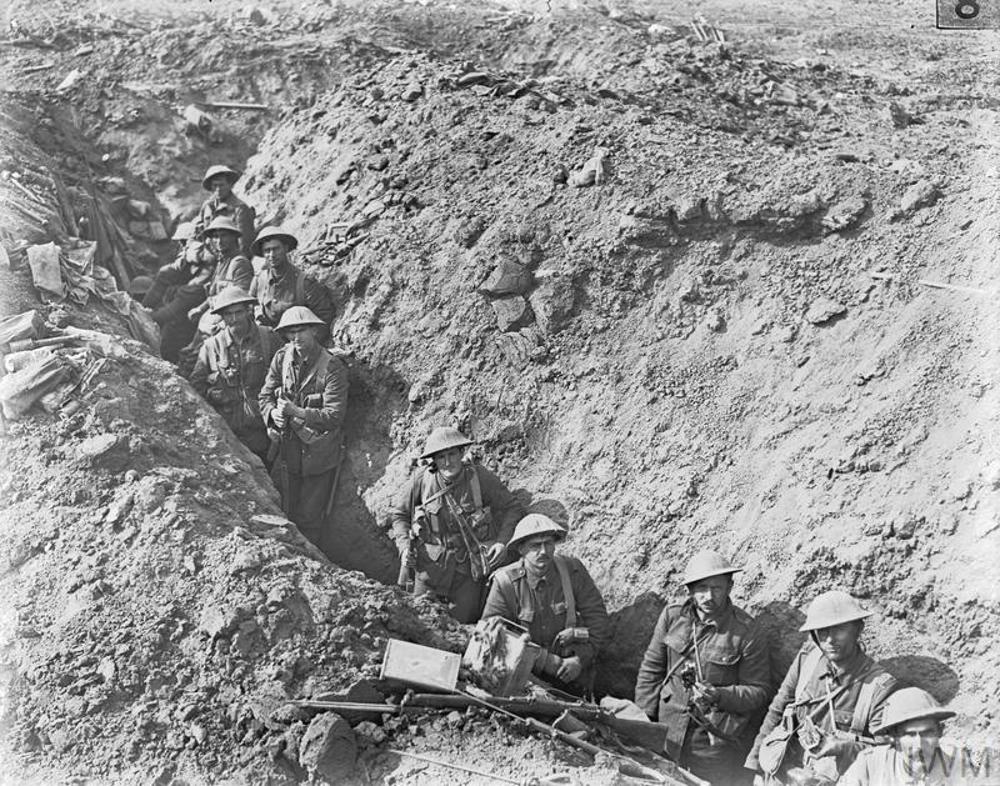 New Zealand infantry men looking up at the camera while standing in a rough, deep communications trench during the Battle of the Somme
