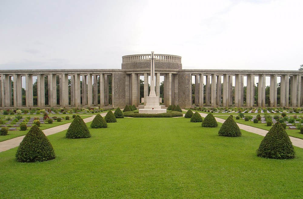 Rangoon Memorial with sculptural lawn and bushes and Cross of Sacrifice visible in the foreground.