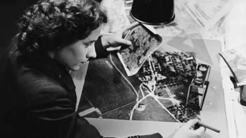 A female Central Interpretation Unit Photo Interpreter studying aerial reconnaissance photos.