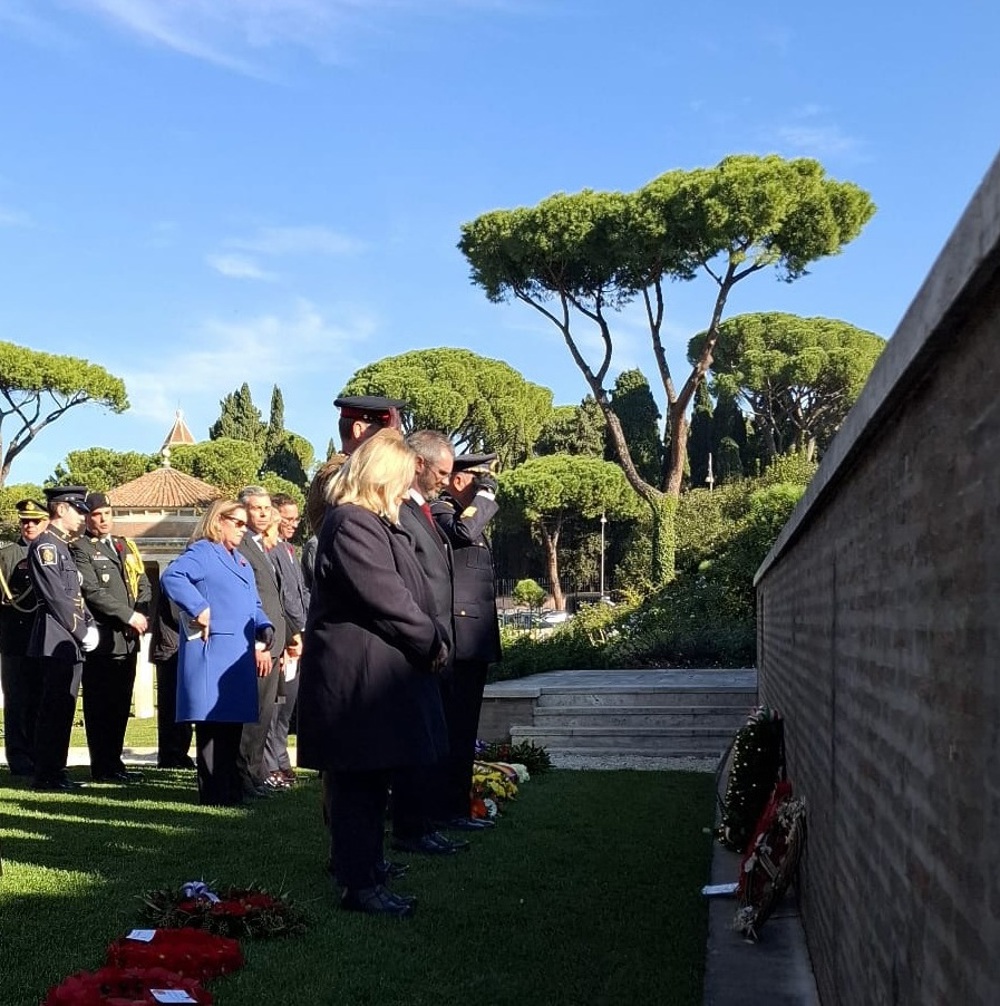 Members of Commonwealth War Graves Commission and military figures bow their heads in respect after laying a wreathe on a memorial in Rome War Cemetery.