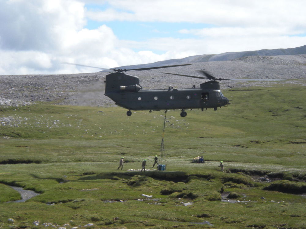 A helicopter hovers as a large stone memorial is winched into placed on a mountainside in Scotland.