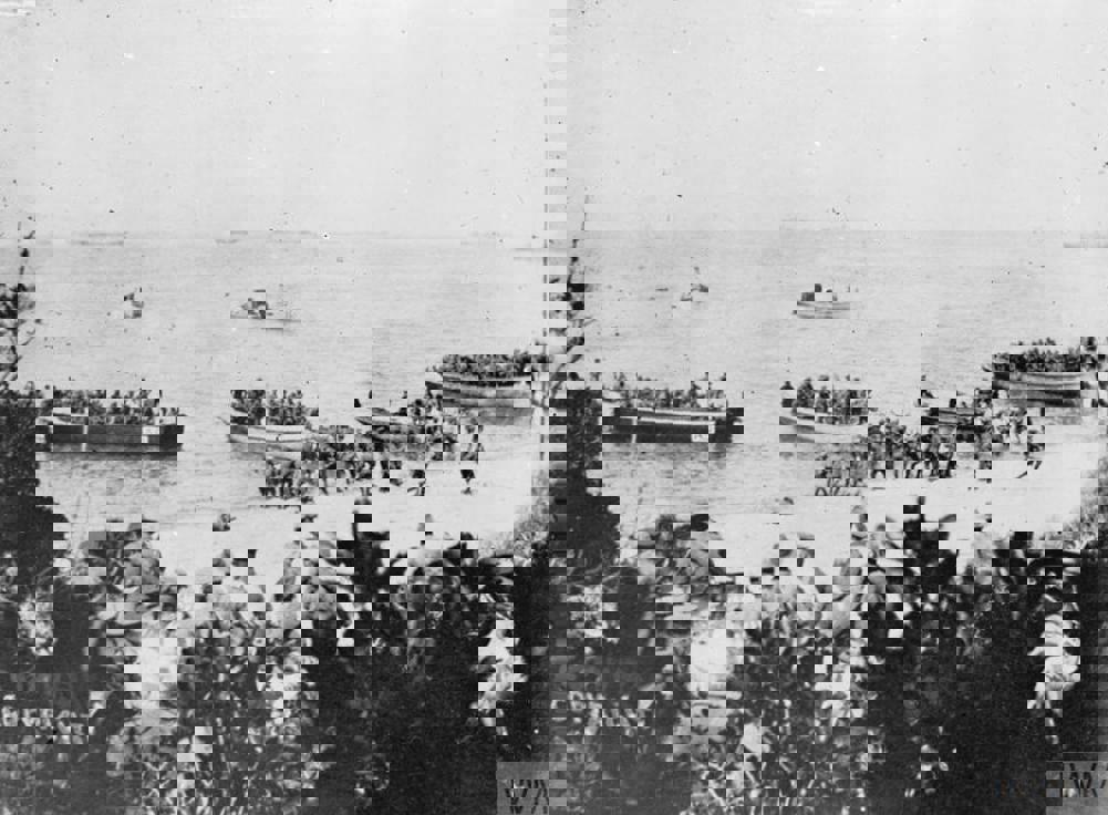 Australian troops coming ashore at Anzac Cove, Gallipoli, on April 15 1915. Most of the men are coming ashore in wooden transport boats. Some officers observe the landings from scrub higher up the beach.