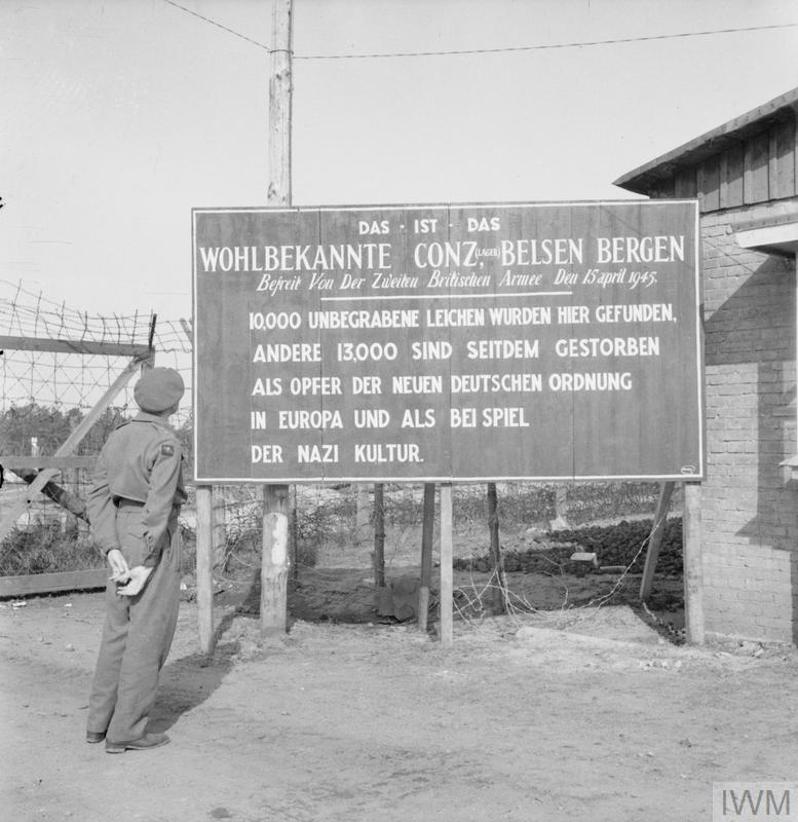 A British soldier looks at a sign erected outside Bergen-Belsen Concentration Camp