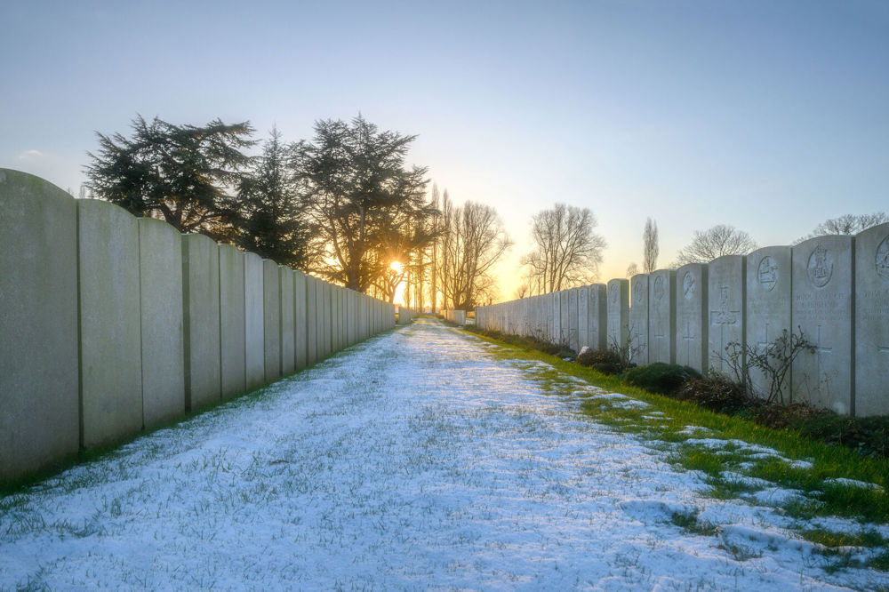 A row of CWGC headstones at Lijssenthoek Military Cemetery. The grass is covered in a thin layer of white frost.