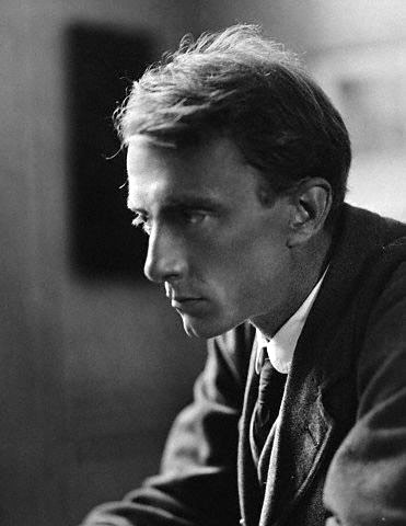 A portrait of Edward Thomas showing a sharp nose and cheekbones. He is in repose in a writing room.