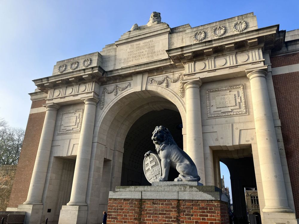 Low angle of the front of the Menin Gate Memorial showing a close up of one of the decorative lion statues ahead of the main arch.