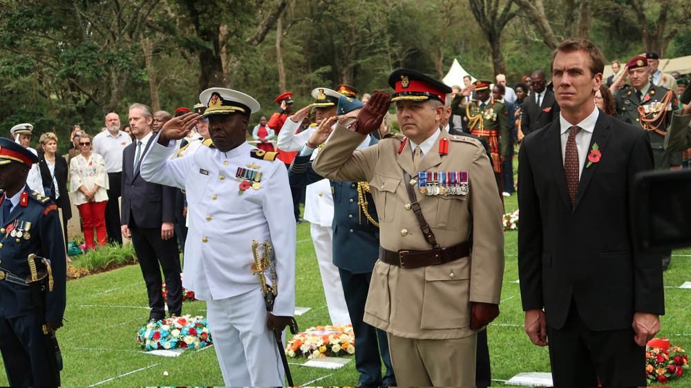Kenya, and British officers salute while civilian politicans stand in solemn contemplation during Remembrance Day ceremonies in Nairobi War Cemetery.