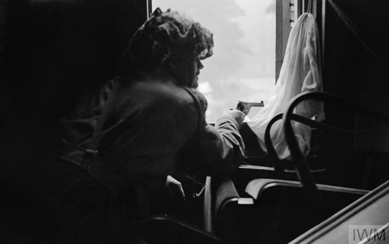 A british Airborne Officer firing a pistol out of the window at the Hartenstein Hotel, Oosterbeek, during the Battle of Arnhem