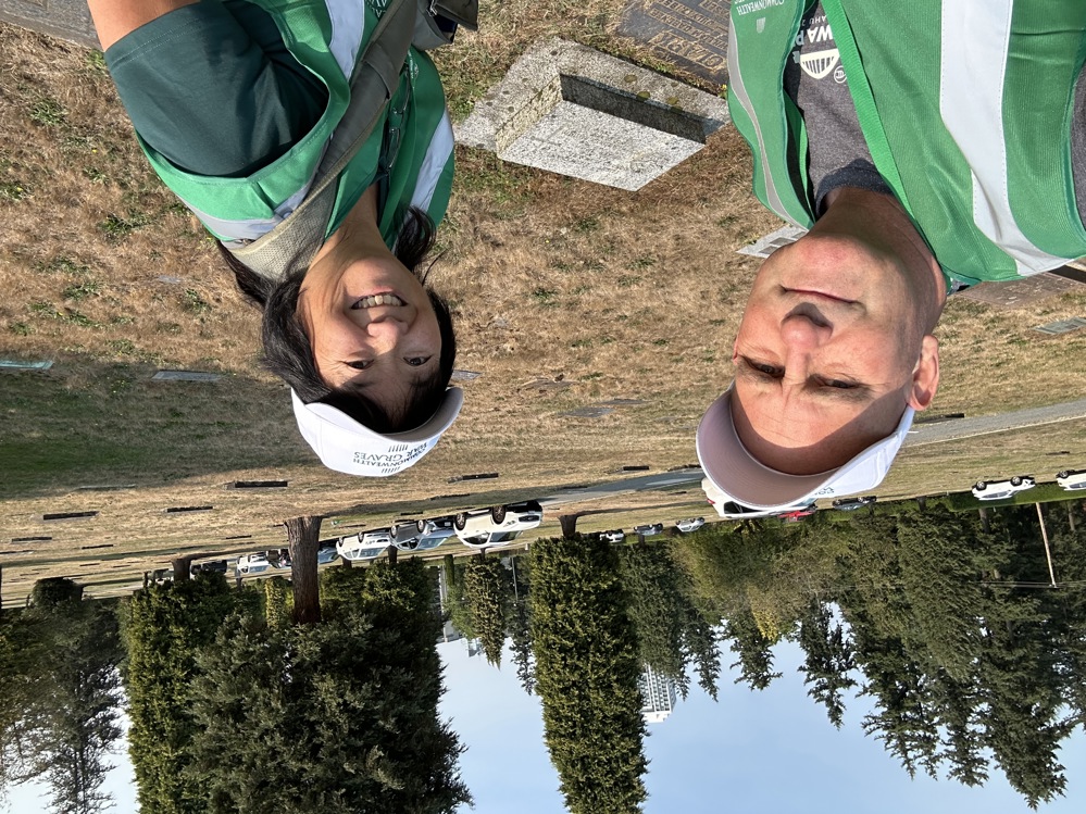 Canadian volunteers Greg, left, and Sue, right, pose next a grave marker in a Canadian cemetery.
