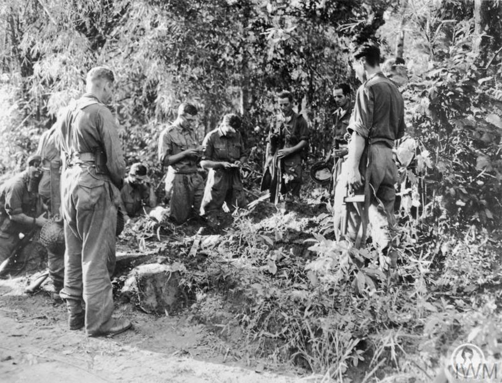 An army chaplain leads a small ceremony over a war grave in jungle brush in Burma, 1945.