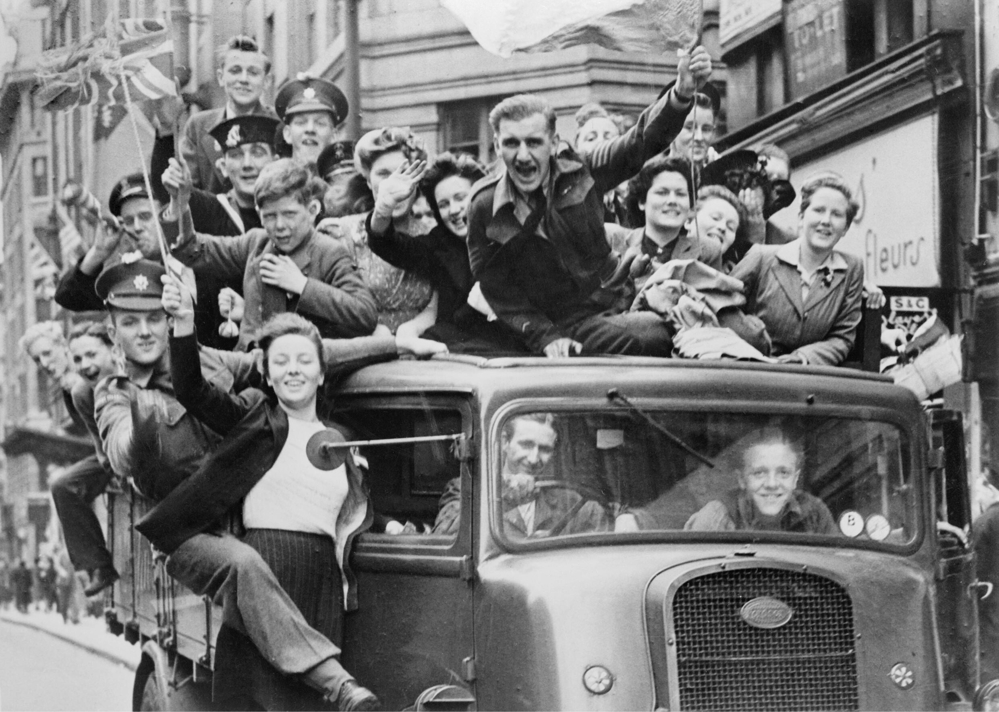 Cvilians and soliders riding in an open-topped Lorry celebrate V-E Day in London circa May 1945.