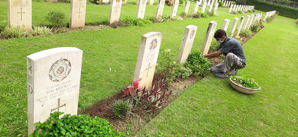A CWGC gardener tending the borders of a headstone row in Ranchi War Cemetery.