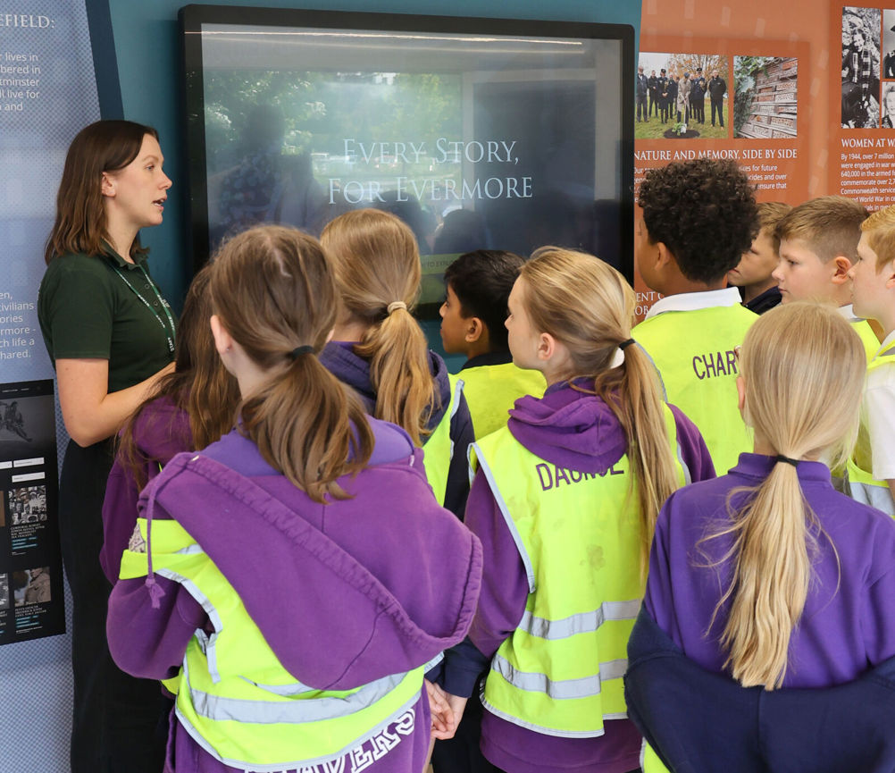 A CWGC public engagement coordinator shows school children the For Evermore digital archive on a large television screen.