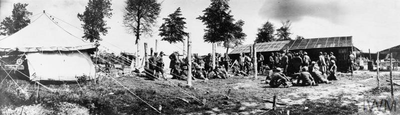 A World War One casualty clearing station showing various huts and wounded soldiers waiting for treatment outside.