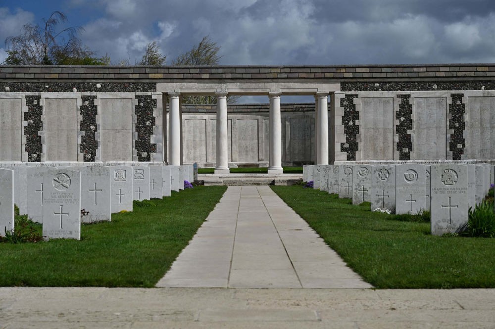Path flanked by headstones leading up to the collanaded entry to a section of the Tyne Cot Memorial.