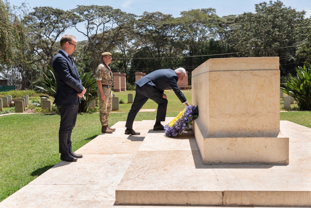 Man lays a wreath on a Stone of Remembrance in a CWGC Kenyan cemetery.