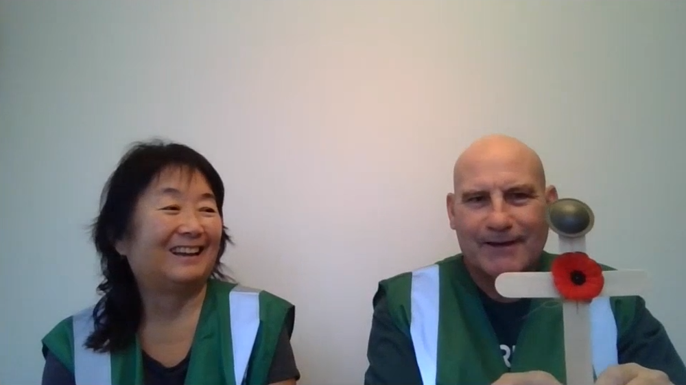 Sue, left, and Greg, holding up a wooden cross with a small red poppy afixed to the centre and a miniature Canadian WW1 helmet perched on top.