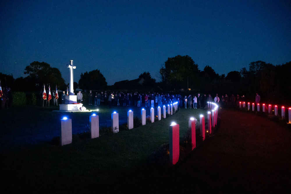 Headstones at Jerusalem War Cemetery, Normandy, illuminated red white and blue for D-Day 80th Anniversary celebrations.