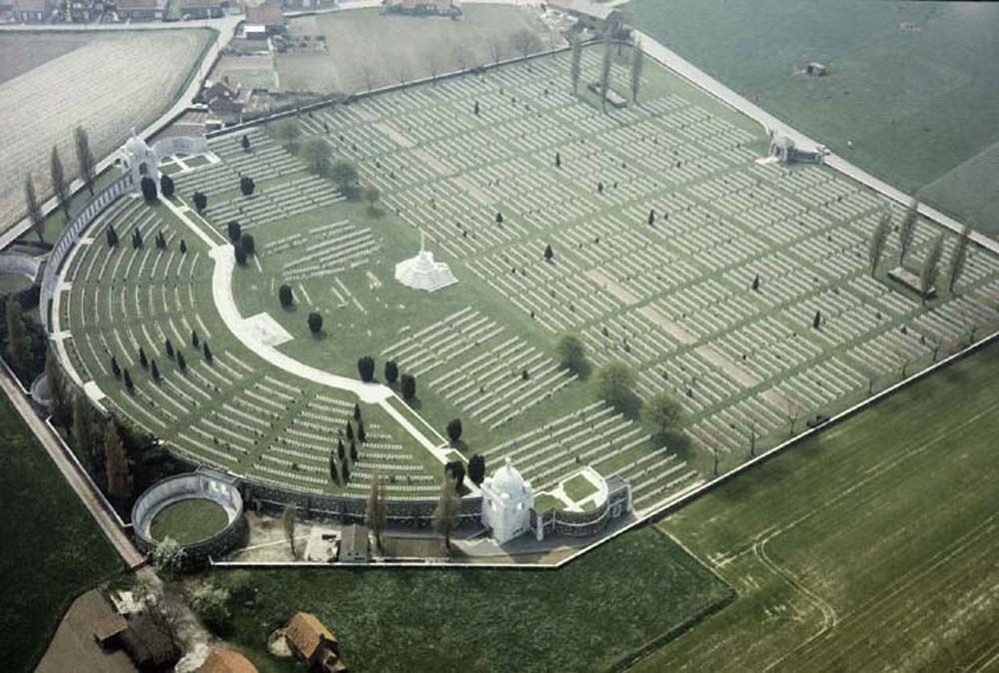 Aerial view of Tyne Cot Cemetery. The entire cemetery is visible, including the curved curtain wall and memorial at the north of the cemetery, leading down to row after row of CWGC headstones.