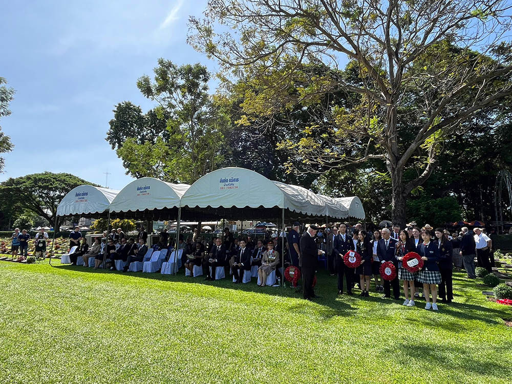 Dignatires and visitors to Chungkai War Cemetery gather under a gazebo to hide from the shade during Remembrance Day ceremonies.