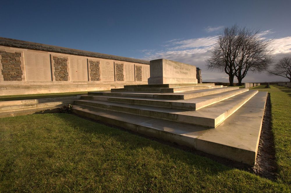 The Stone of Remembrance and New Zealand Memorial at Caterpillar Valley. Two tall trees are visible in the background.
