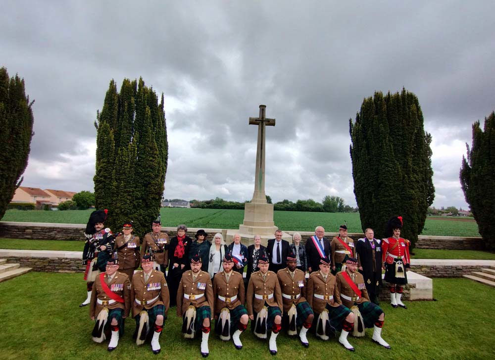 Members of 2 Scots with six members of the Gemmell family in front of the Cross of Sacrifice in Woburn Abbey Cemetery.