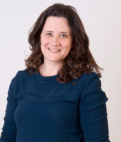 Portrait of Harriet wearing a dark blue dress against a white background.