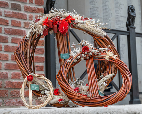 Reed wreaths decorated with flowers and reed tips laid on the Menin Gate memorial.