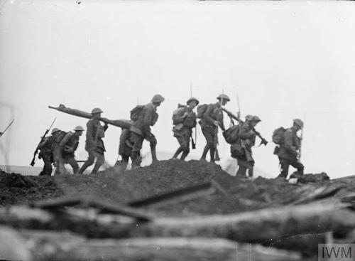 A unit of British soldiers troops over muddy ground during the First World War.