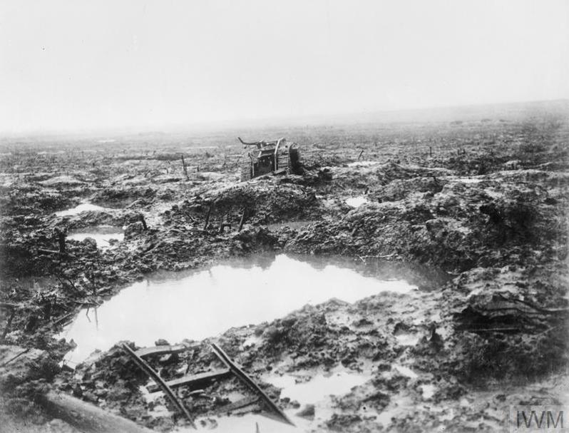 Mud-soaked battlefield with a rainwater-filled crater at Passchendaele. A smashed artillery gun can be seen in the background.