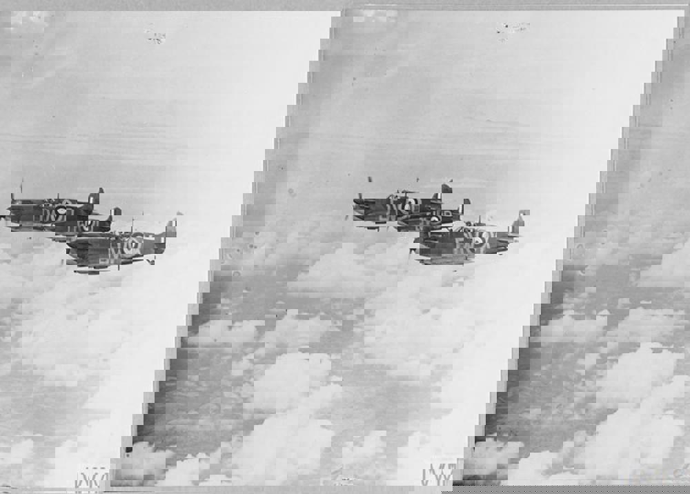 Thee Spitefire fighter planes flying in formation high above the clouds.