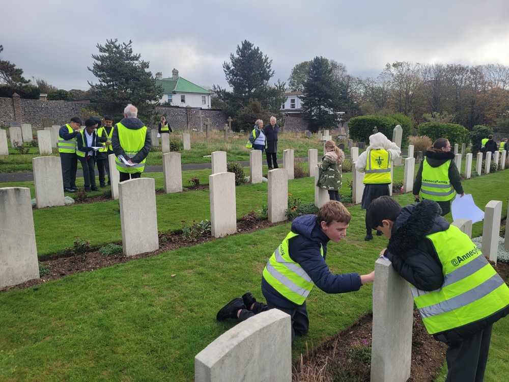 Schoolchildren volunteers helping clean headstones in a cemetery.