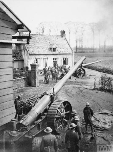 British artillery crews stand around a 6-inch artillery piece next to a few nondescript buildings.