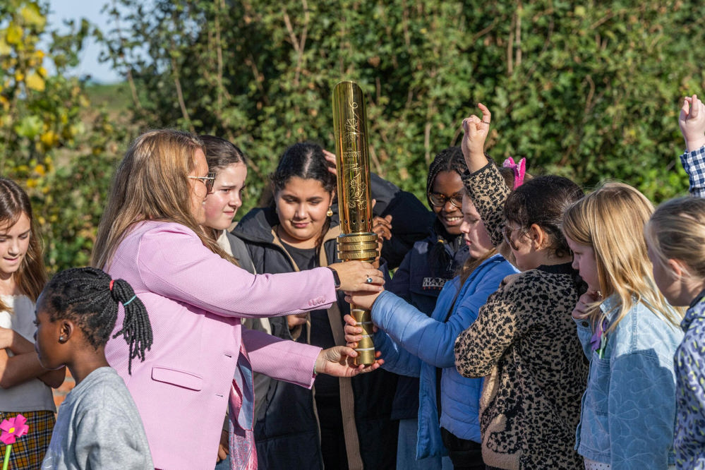 A CWGC staff member hands the Torch for Peace over to Belgian schoolchildren.