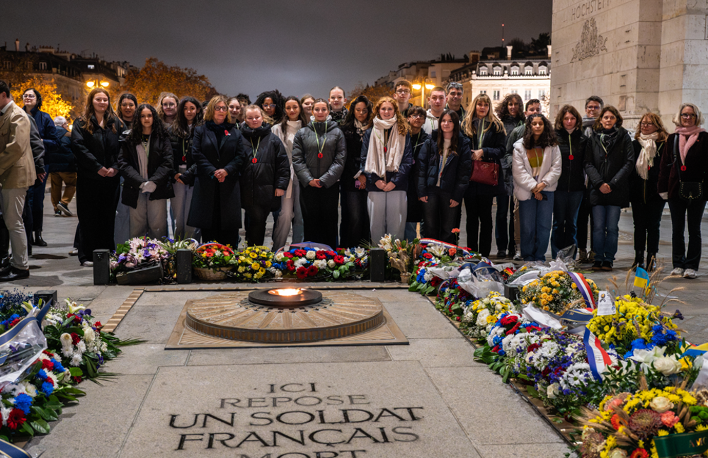 Group of Teenageers stand solmenly around the Eternal Flame at the Arc de Triomphe.