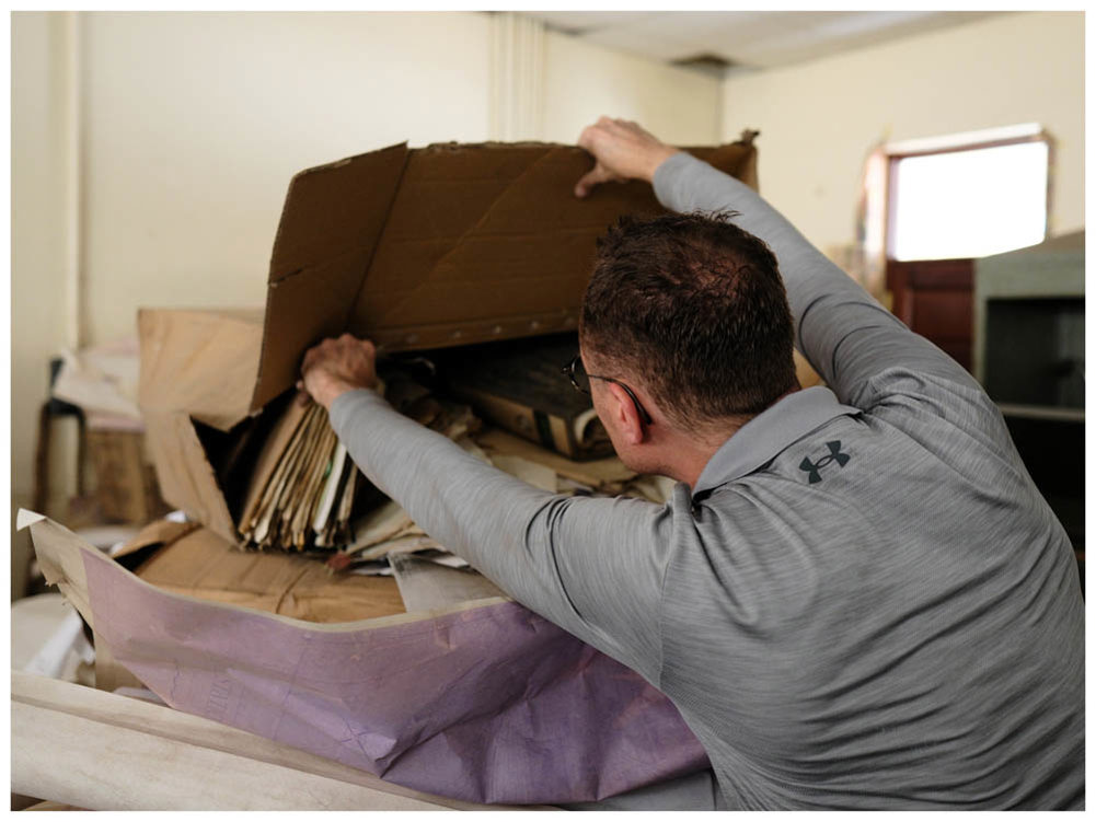 A man opening a cardboard box to retrieve folders containing WW1 personnel files.