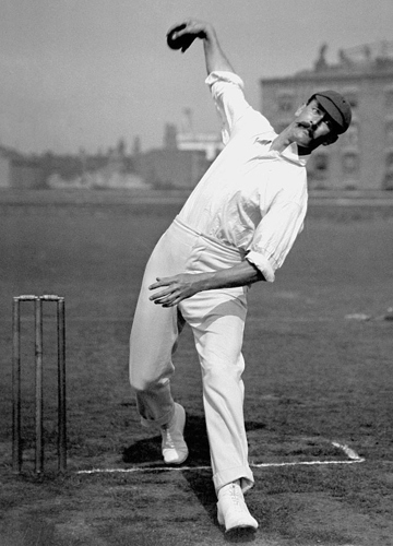 Cricketer Reggie Schwarz bowling in his cricket whites with an arching overhand throw.