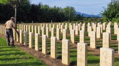 A man gardens around the headstones at Cassino war cemetery