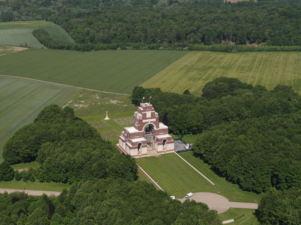 Overhead view of the Thiepval Memorial set amidst a clearing and flanked on both sides by woodland.