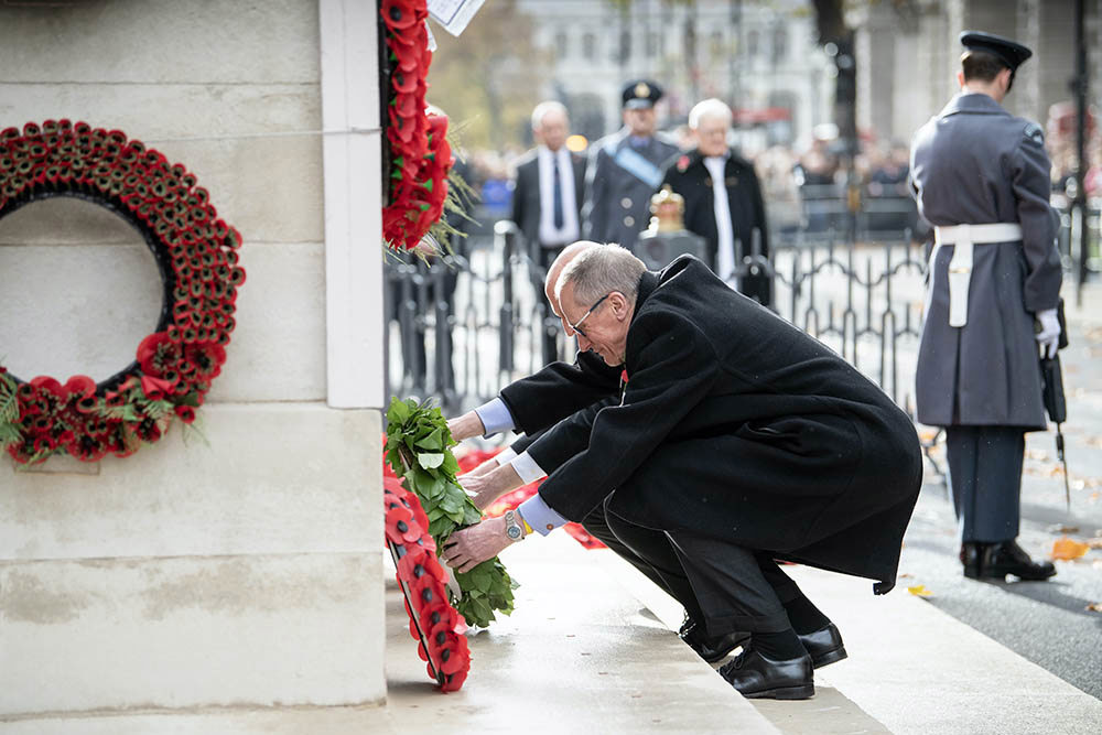 Men lay poppy wreaths on the Cenotaph for Remembrance Day 2025.