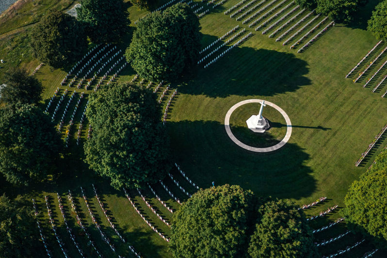 Bayeux War Cemetery showing circular rows of headstones around a central Cross of Sacrifice.