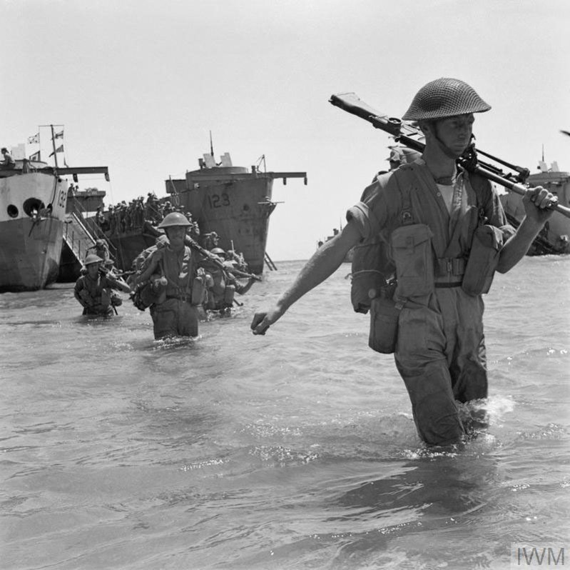 British soldier holding a machine gun wades ashore on Sicily